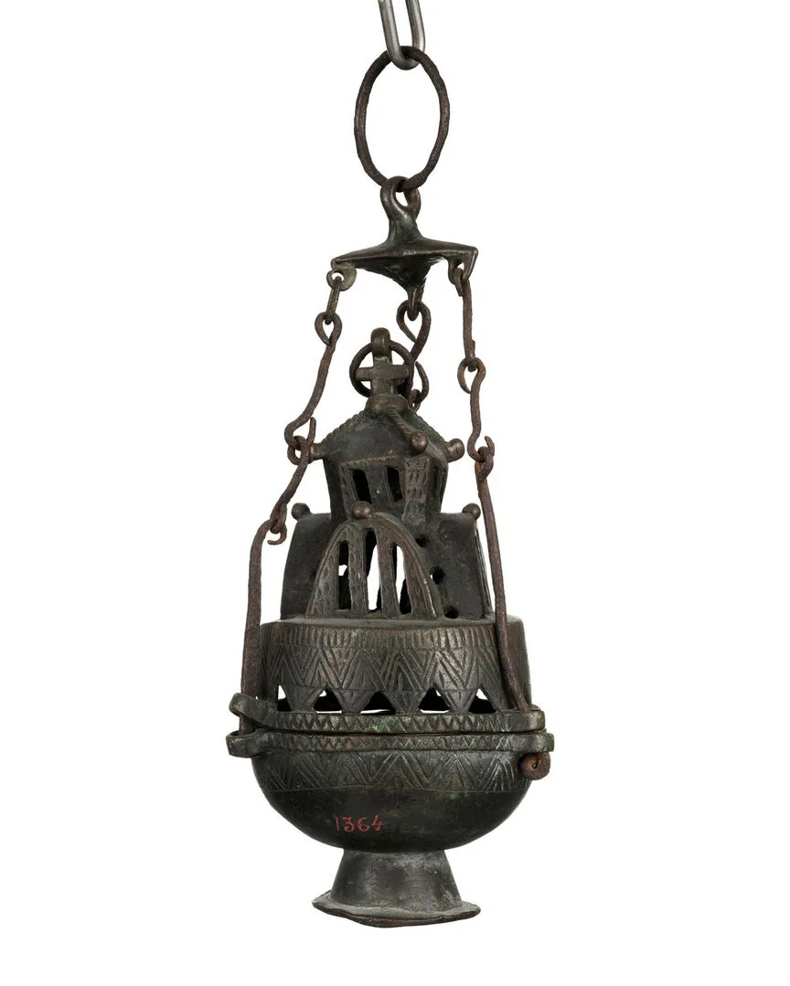 A dark metal object in tiers hanging from three chains connnected to a ring.