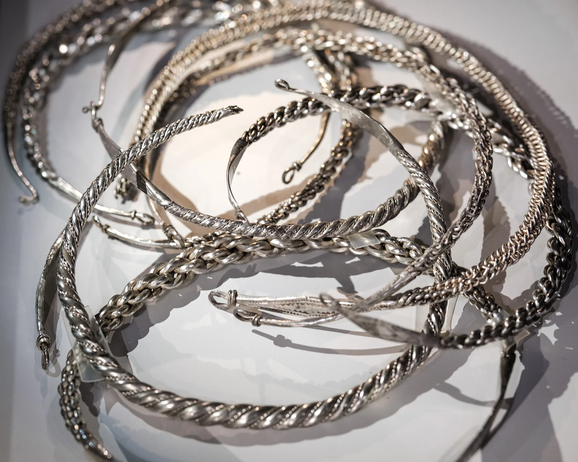 Parts of a silver treasure displayed in a museum case.