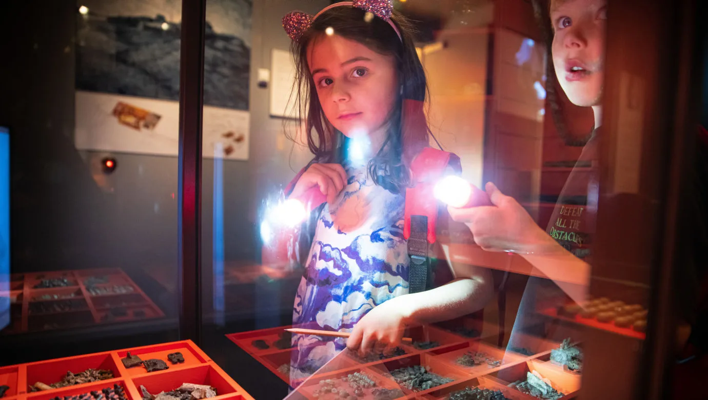 Två barn upptäcker museet med ficklampor.