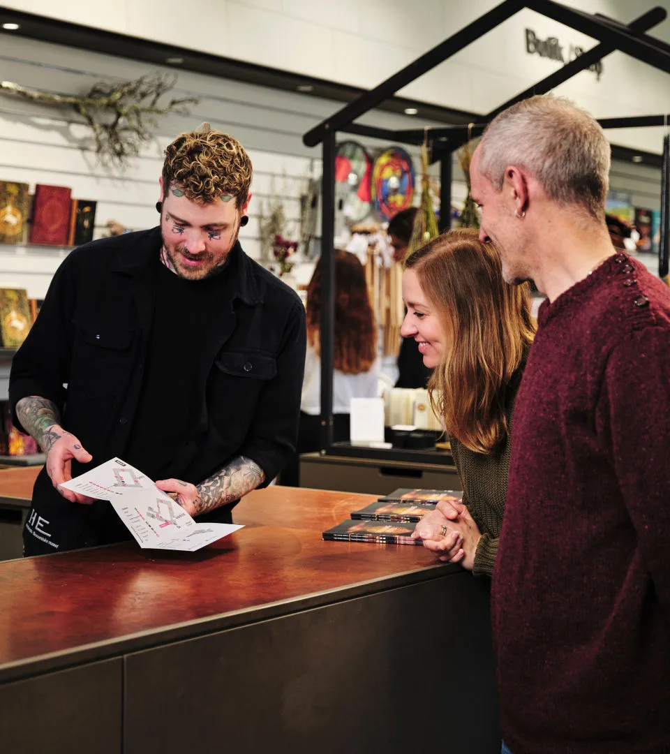 Museipersonal hjälper två besökare i entrén till museet