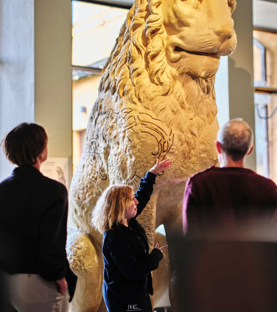 Visitors admiring a sculpture of a Pireus lion 