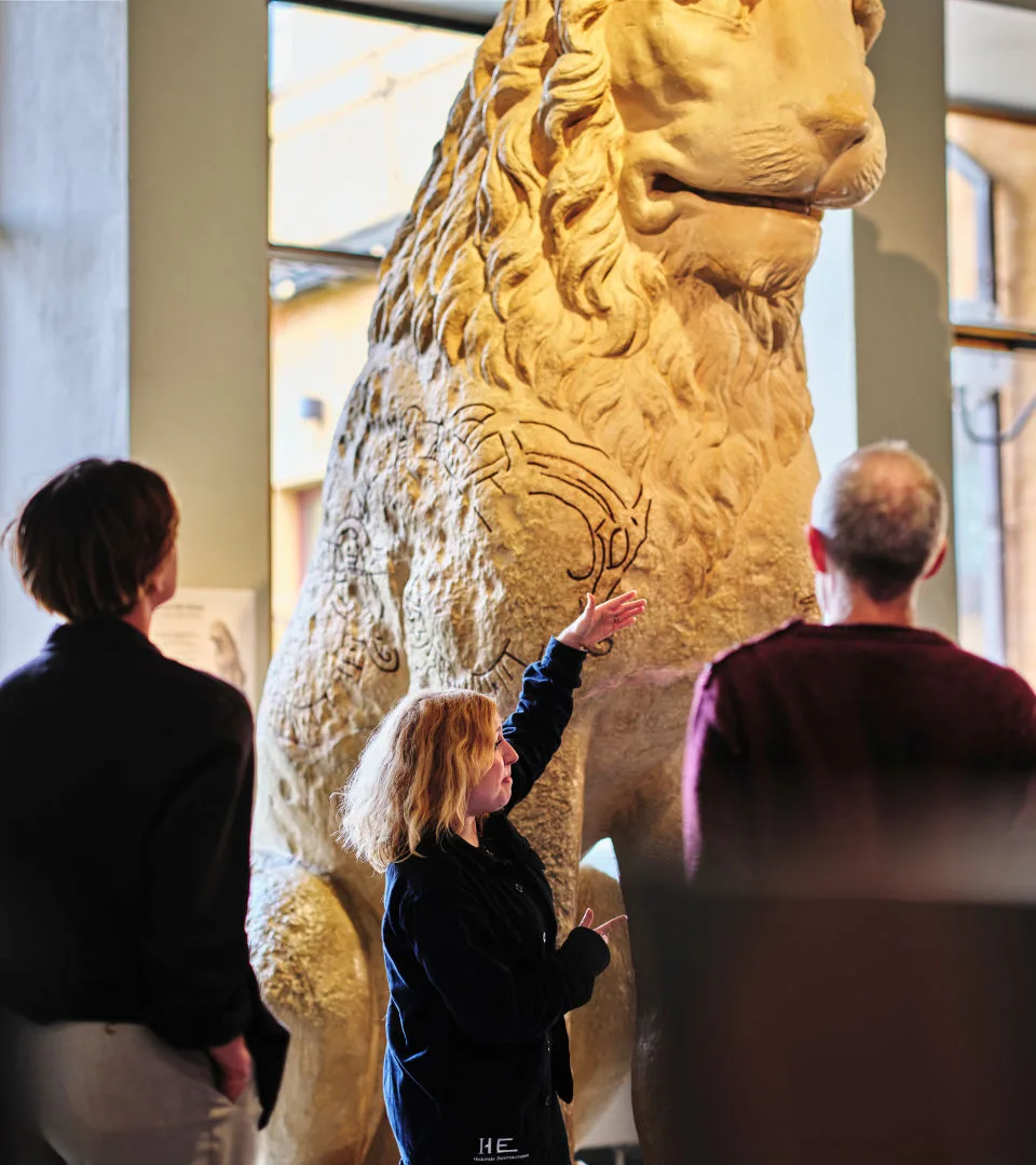 A group of museum visitors listening to a guide.