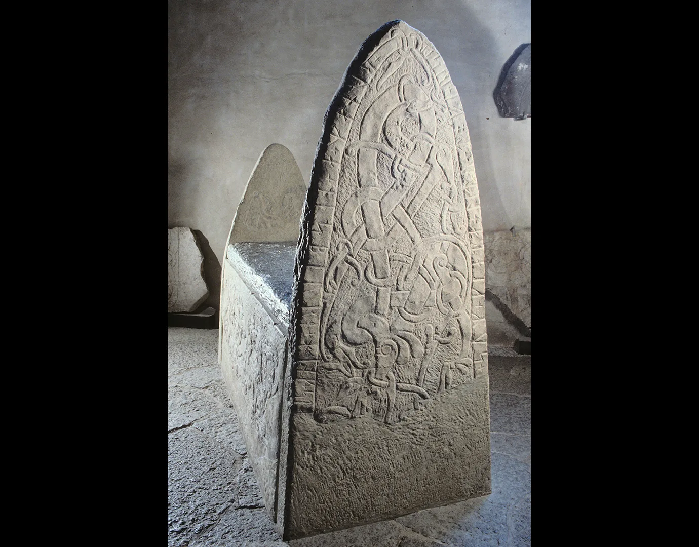 A grey stone coffin with high, pointed ends.