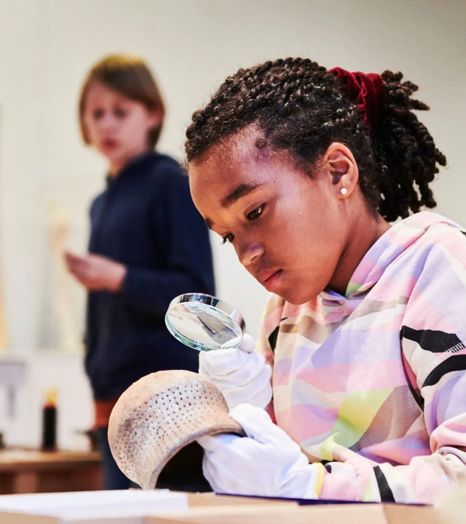 Barn undersöker ett föremål med hjälp av ett förstoringsglas.