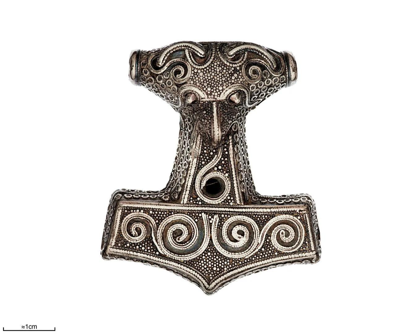 A hammer shaped pendant with elaborate decoration turning the hammer into part animal, part human.