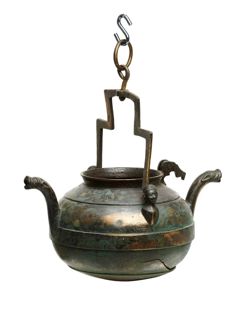 A bronze jug with two spouts and a handle.
