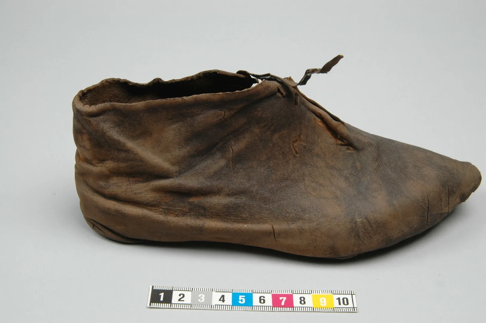 Sko i läder, med veck och snöre som sticker upp