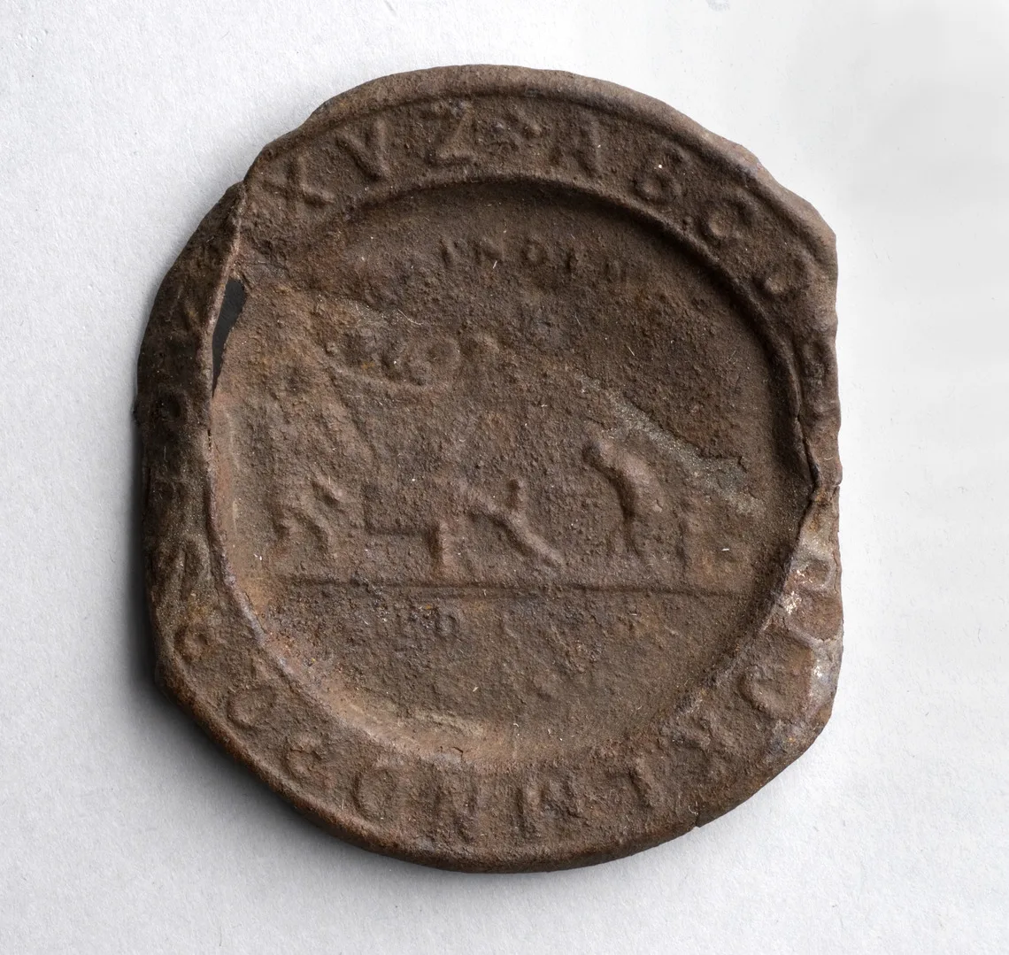 Brunt, runt föremål med otydlig inskription med bokstäver, människor och djur