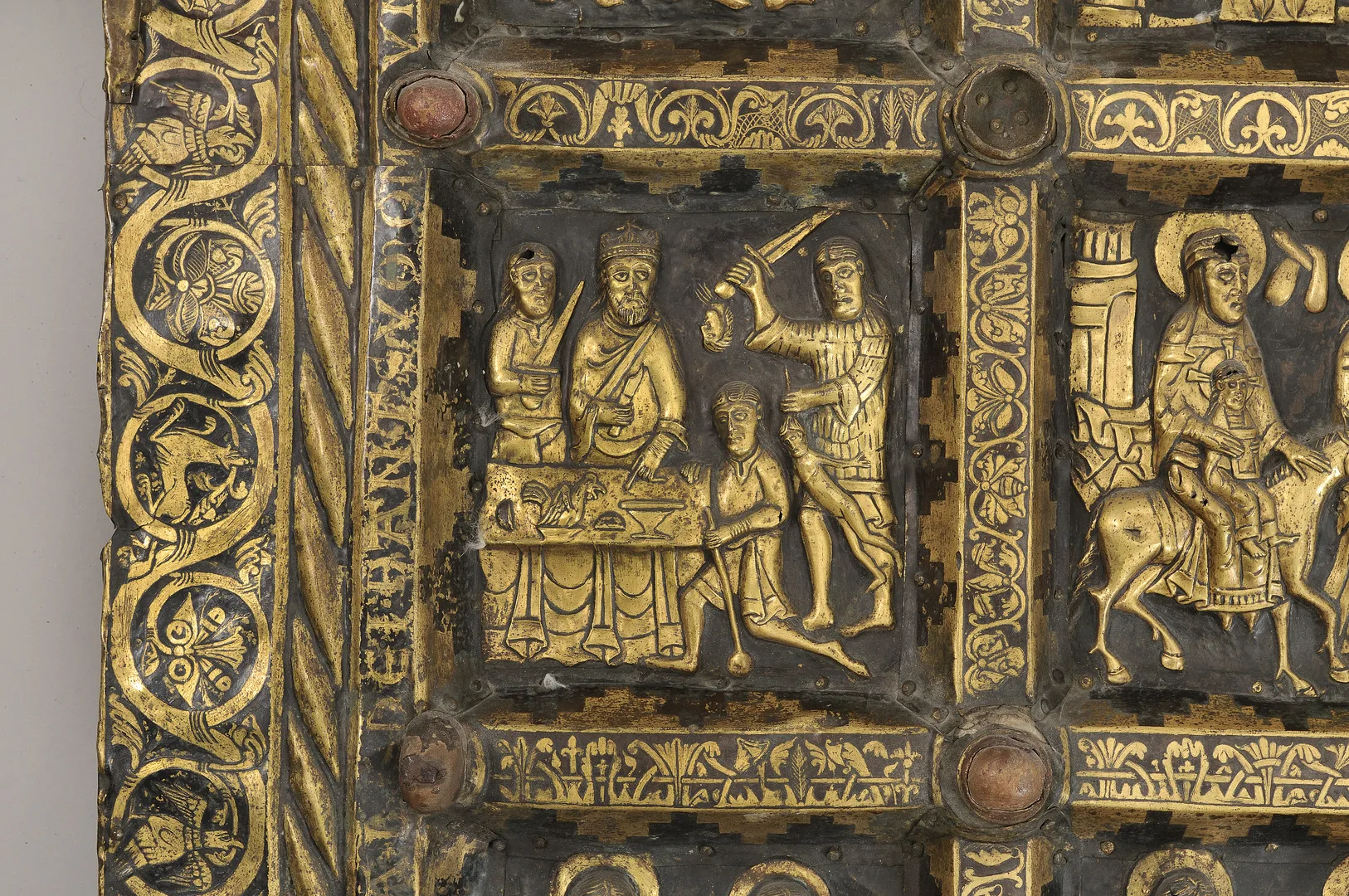 Förgylld scen med fyra personer med svärd och en tupp på ett bord,