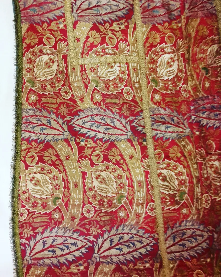 Details of a chasuble, showing an exquisite pattern of flowers in silver and gold on a red background 