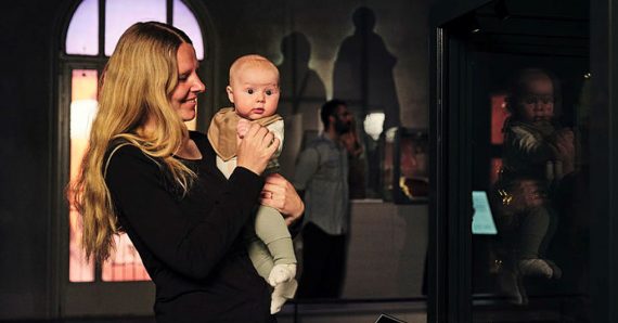 En person står i en utställning med en bebis i sin famn.