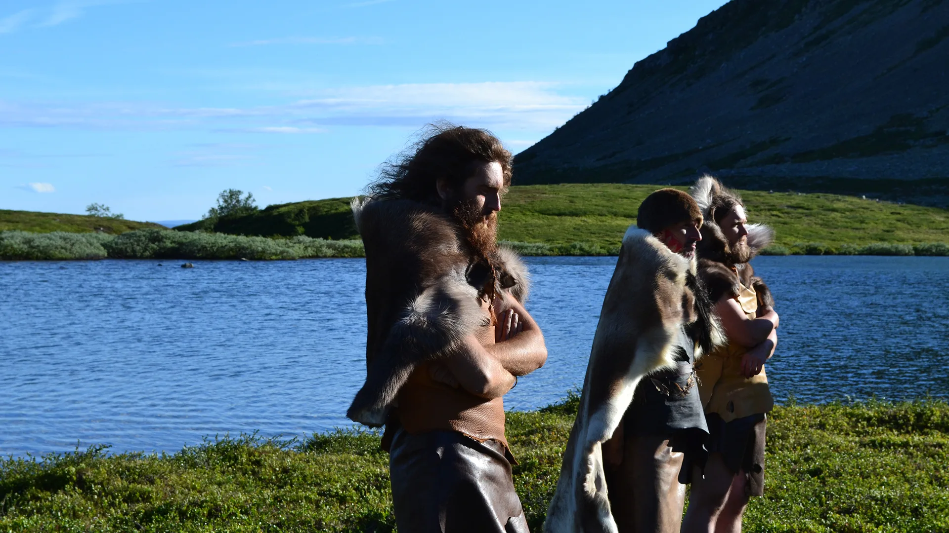 People in fur walking by a body of water