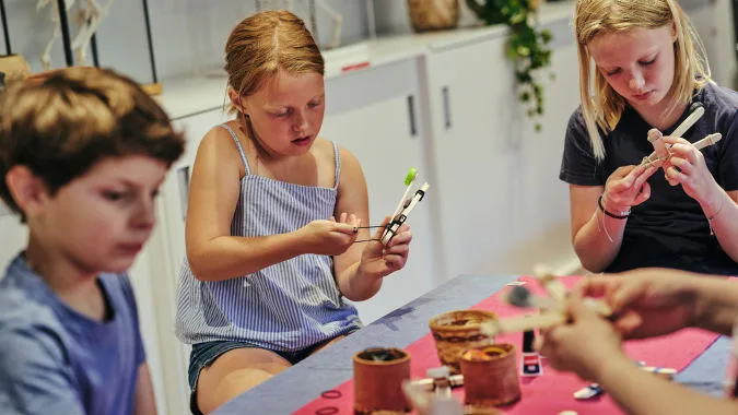 Barn som sitter och pysslar i museets verkstad.