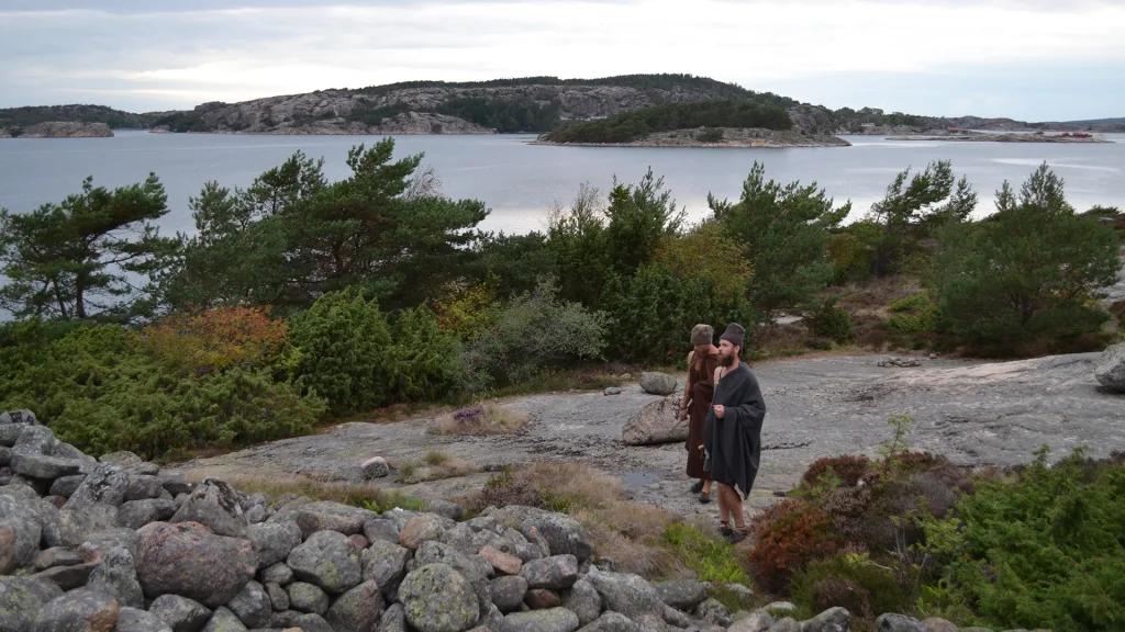 Två personer utklädda i bronsålders-tyger står nära havet