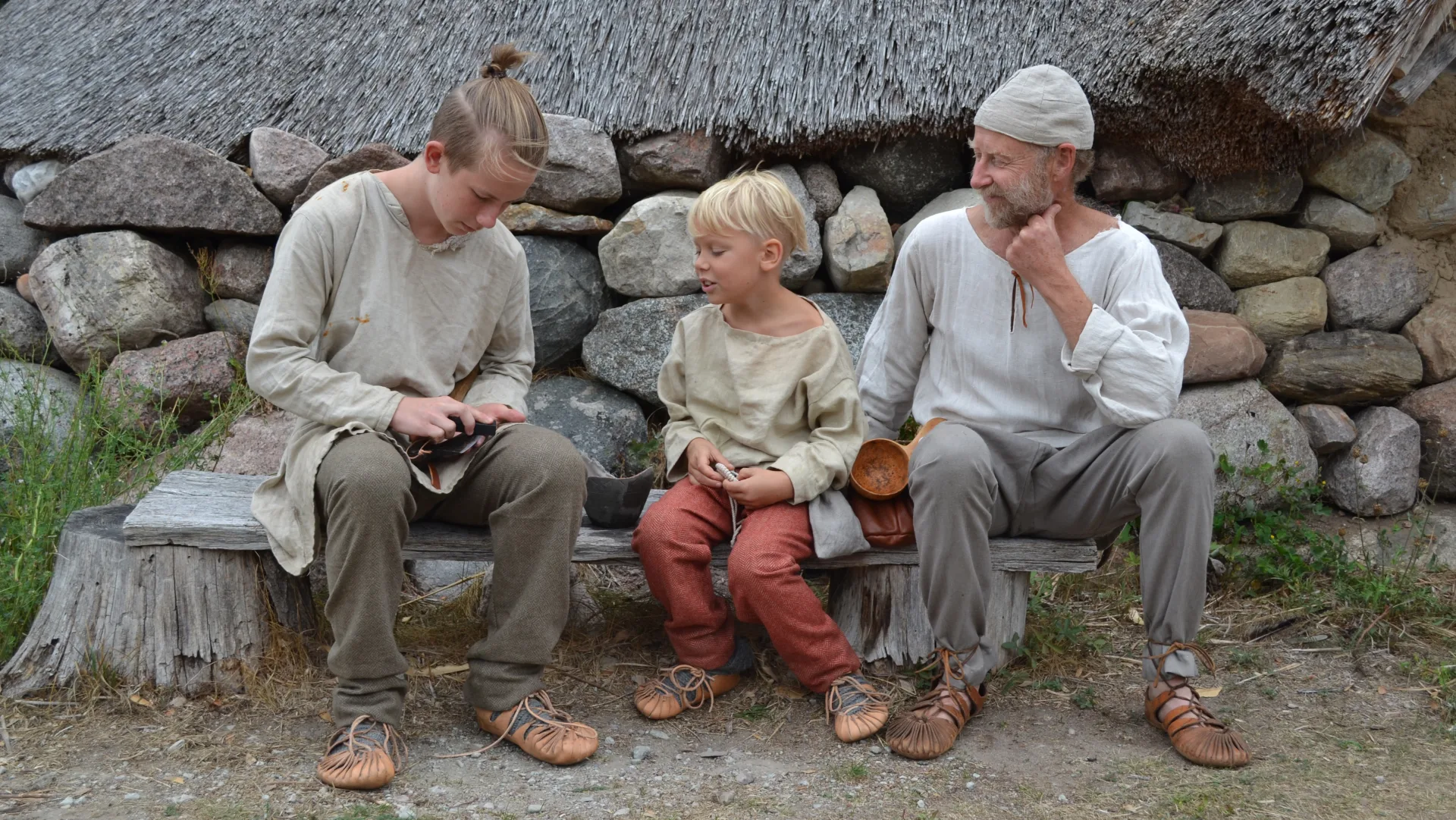 Två barn och en vuxen sittandes på en bänk