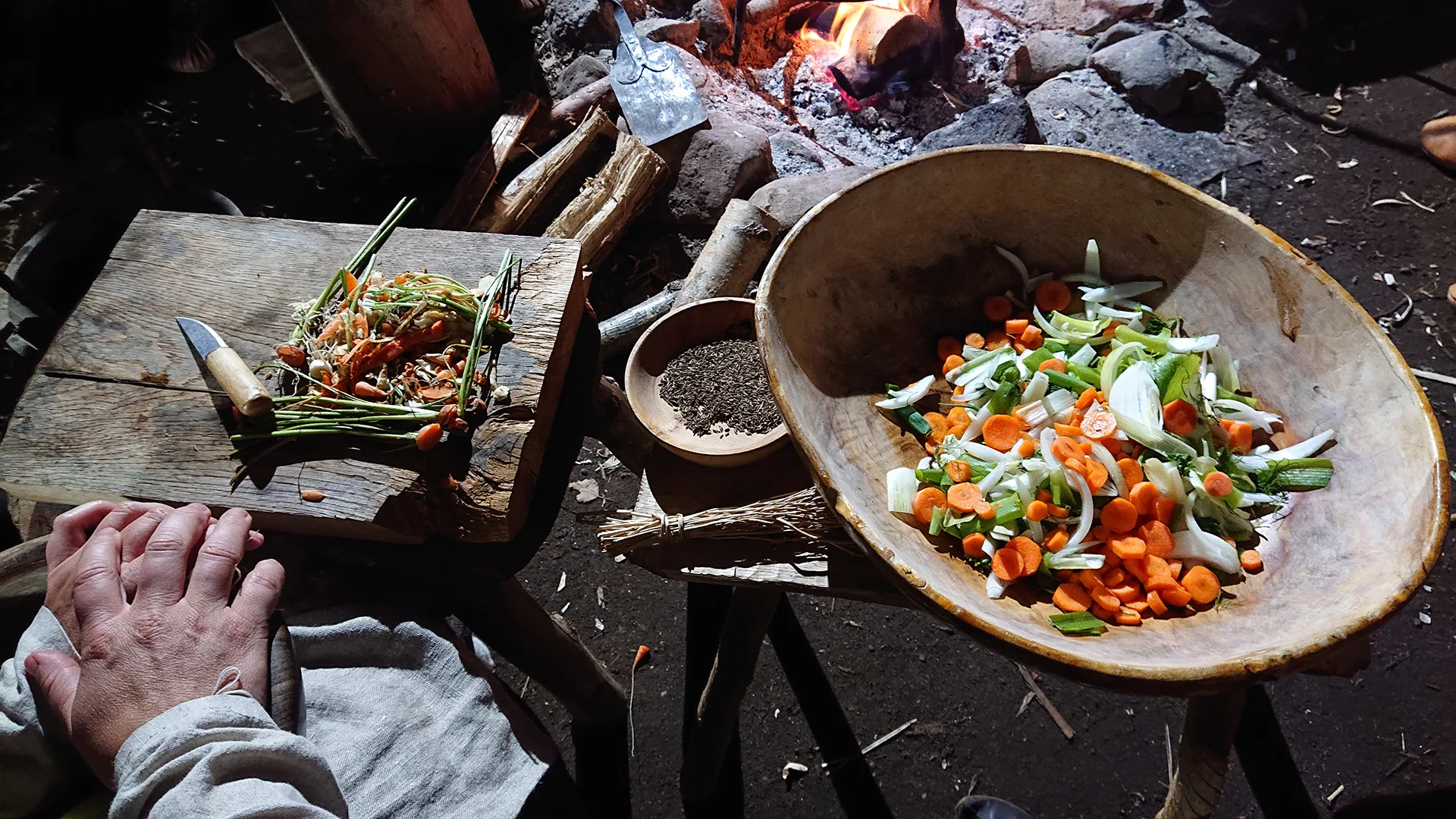 Reconstruction of Iron Age food preparation. A bowl with vegetables, a cuttingboard and knife, and some spices are seen.