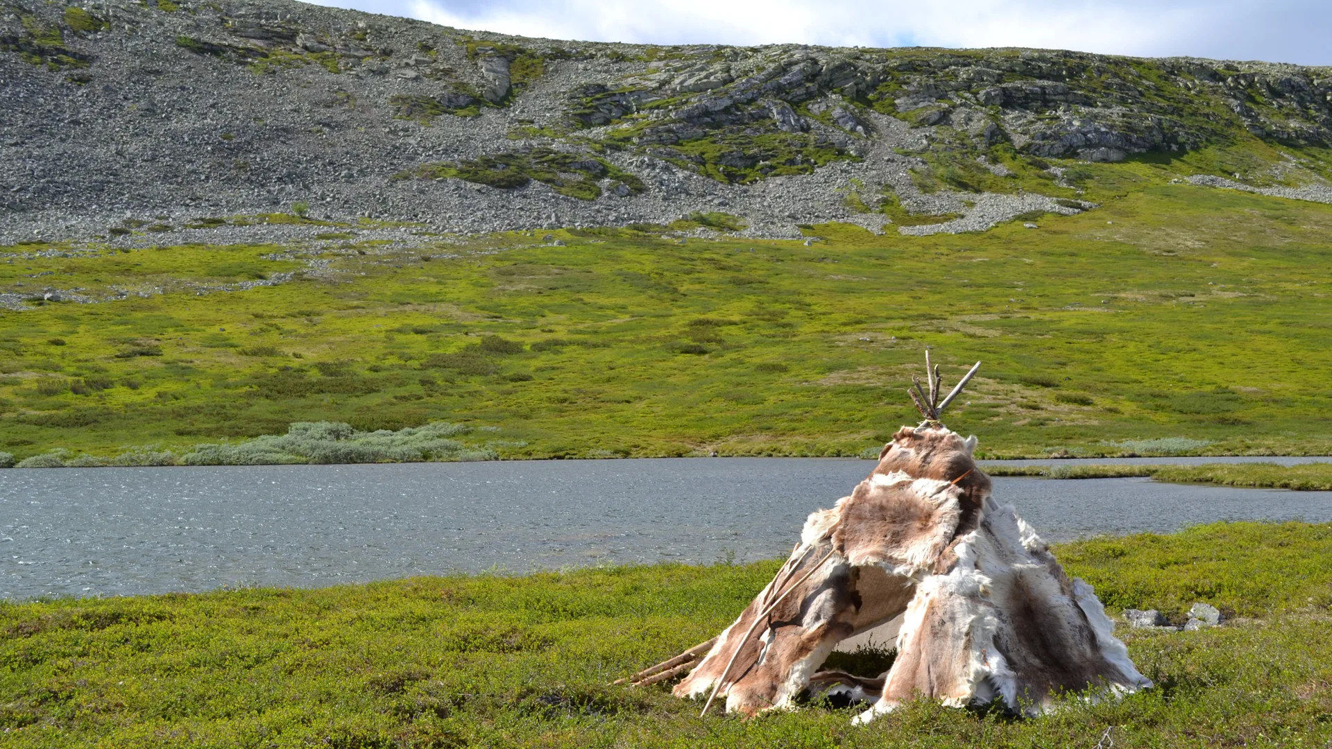 Fur-clad teepee in a landscape with water and rocks