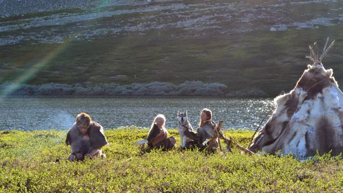 People wearing fur sitting by a teepee