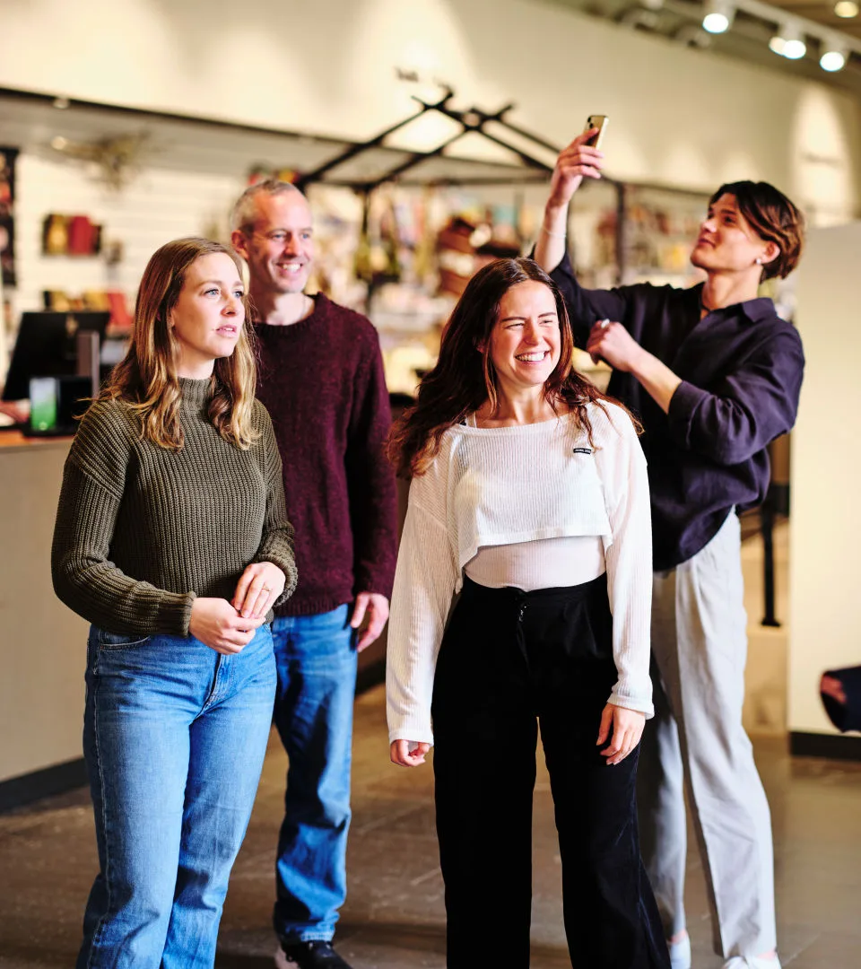 En grupp besökare. I bakgrunden syns personal på museet stå i kassan.