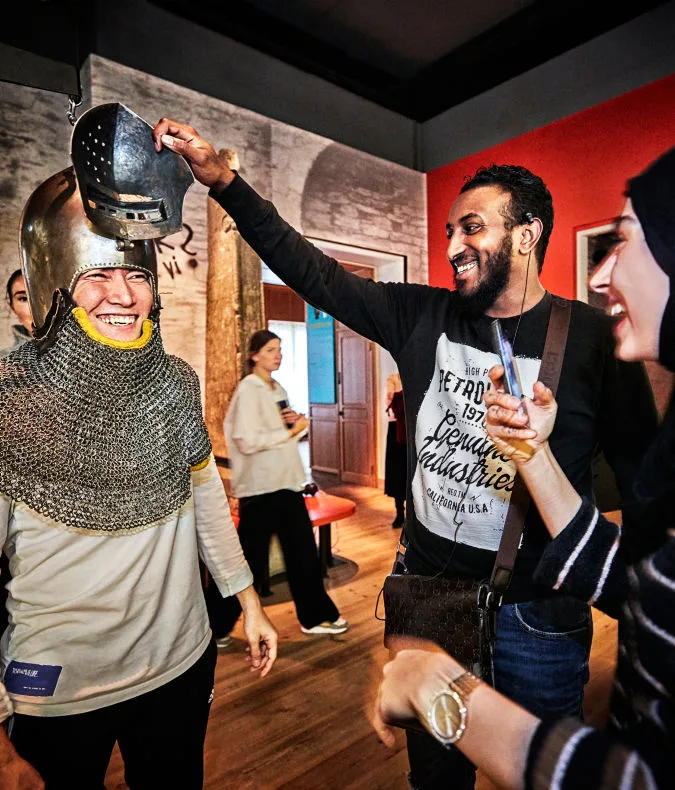 A person tries on a helmet. Two other people stand nearby, and one person is taking a photo.