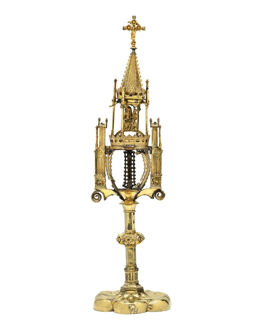 Förgylld medeltida relikbehållare med tornform och kors upptill.