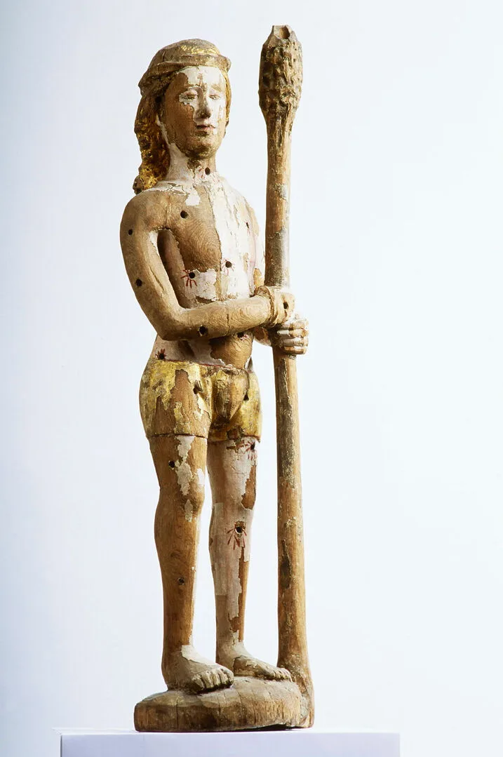 Skulptur av man ståendes med en stav