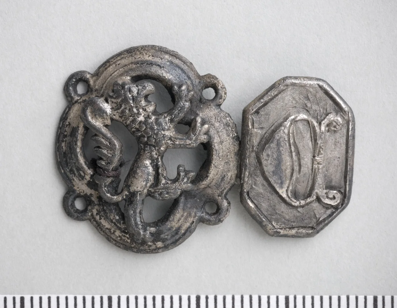 Metal jewelry in two parts, one featuring an animal motif, a lion