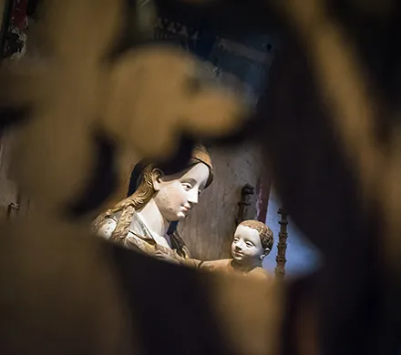 Skulptur av Maria med barnet skymtar i mitten av ett annat mörkt föremål