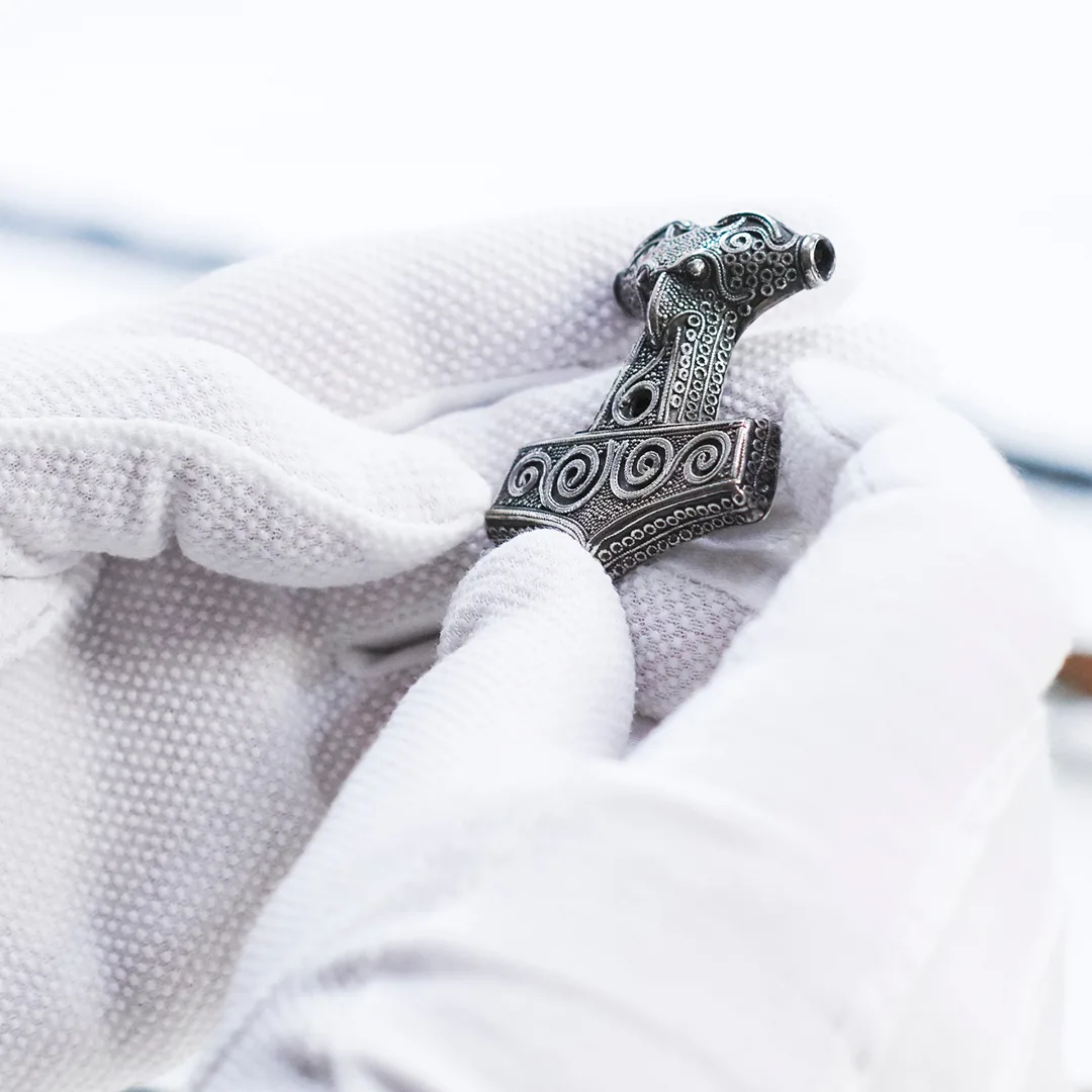 Händer med vita handskar som håller en torshammare,