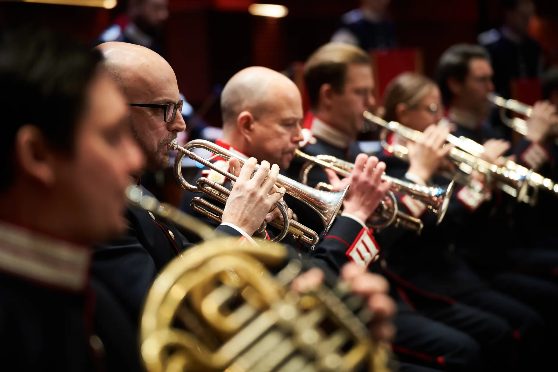 Personer i uniform sitter på rad och spelar olika instrument.