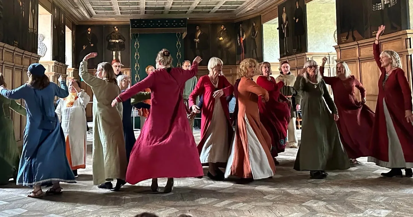 Personer som dansar runt i färgglada dräkter.