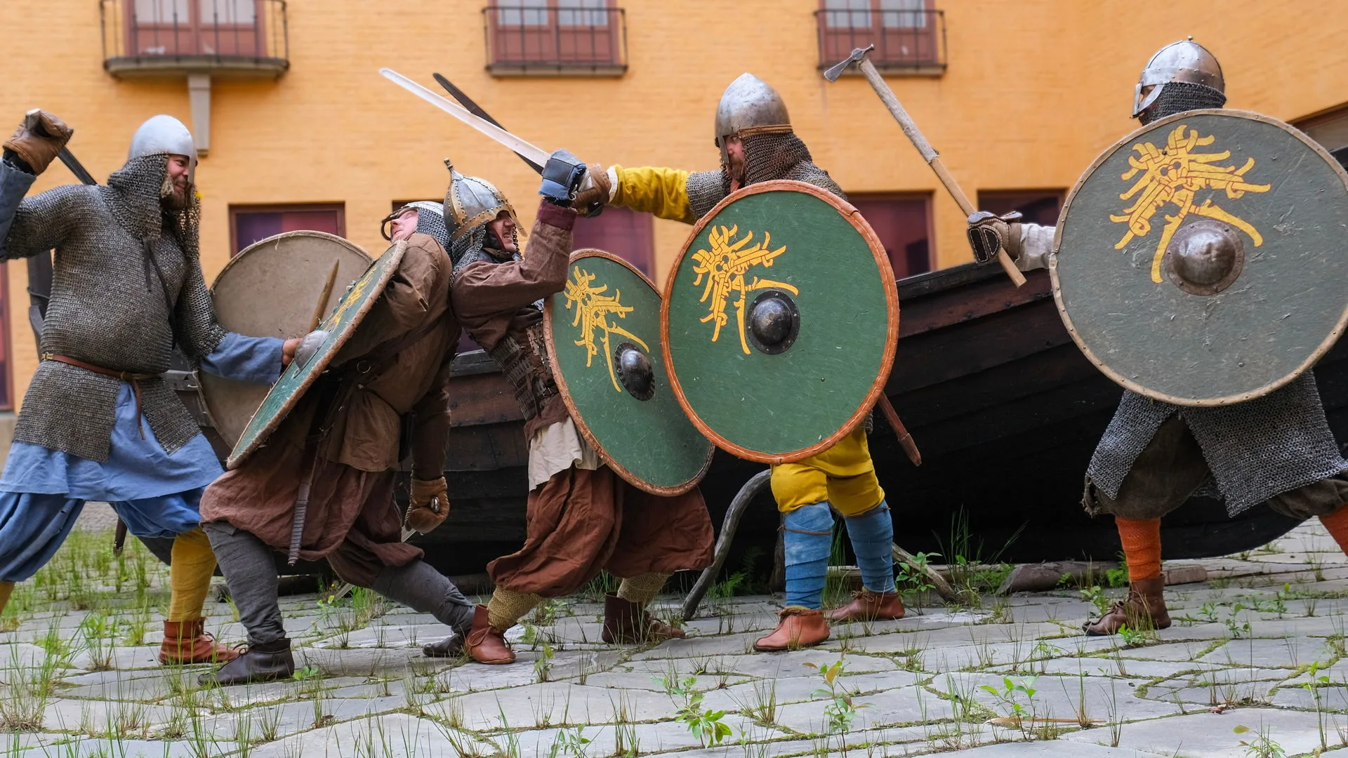 4 personer i vikingakläder iscensätter en strid framför krampbacken på museets innergård