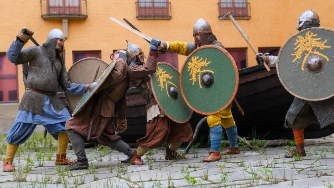 personer med vikingakläder och svärd krigar
