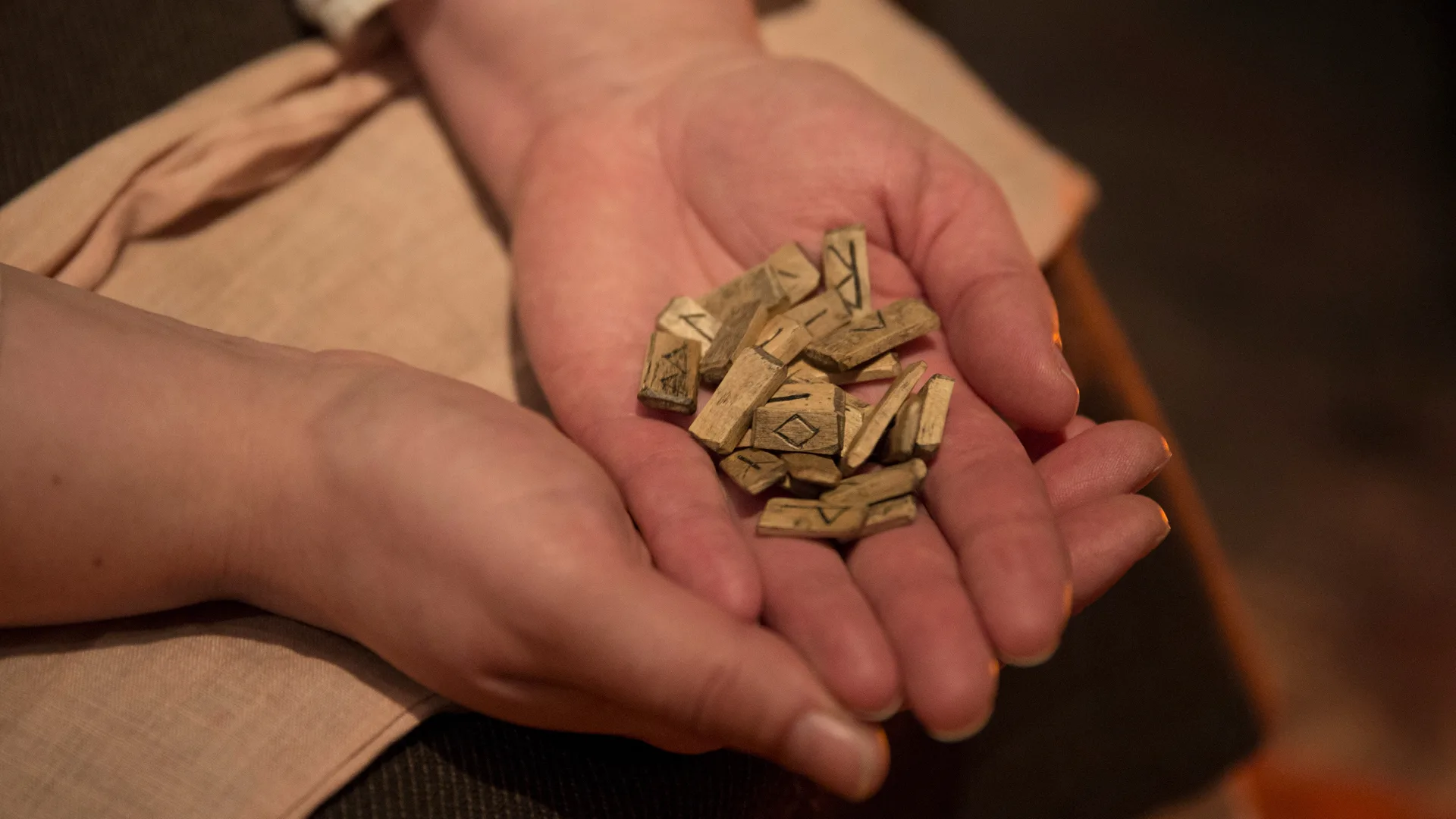 Person håller små bitar med runor i sina händer