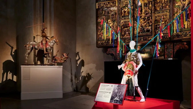 Mannequin in front of an altarpiece and sculpure with Saint George on a horse